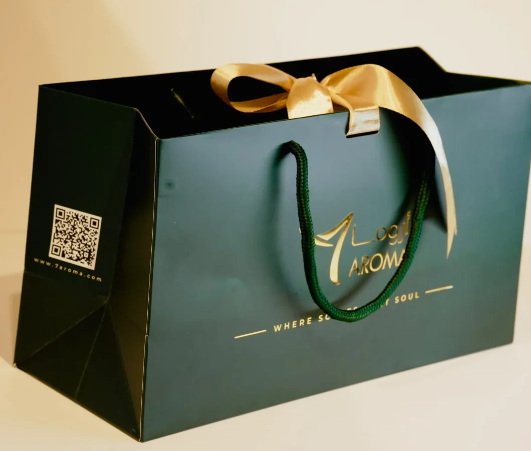 A deep green 7 AROMA shopping bag tied with a gold satin ribbon
